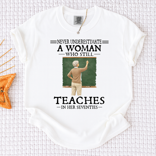Comfort Colors Never Underestimate A Woman Who Still Teaches in Her Seventies T-Shirt – Custom Gift for Teachers
